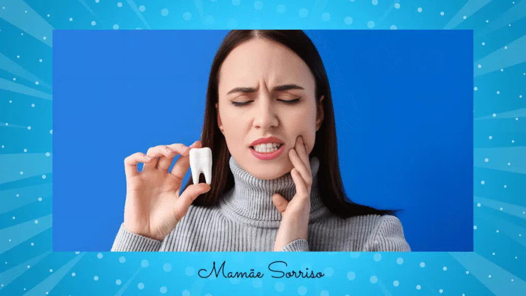 Woman holding side of jaw with expression of pain in teeth while holding tooth model, blue background